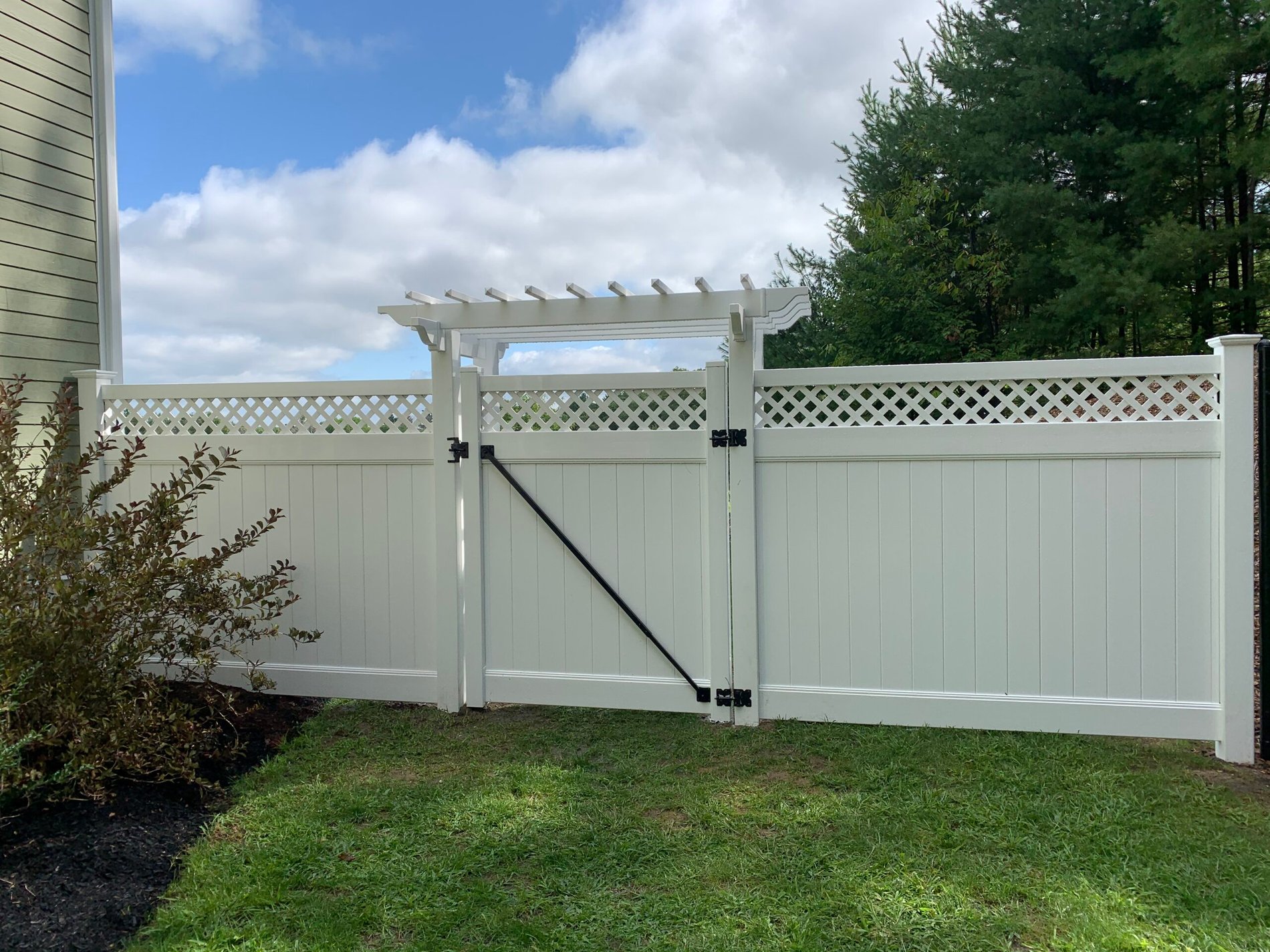 White vinyl fence with a lattice arbor gate installed by Prime Fence in Worcester